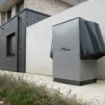 Zewnętrzna pompa ciepła alpha innotec przy nowoczesnym domu
