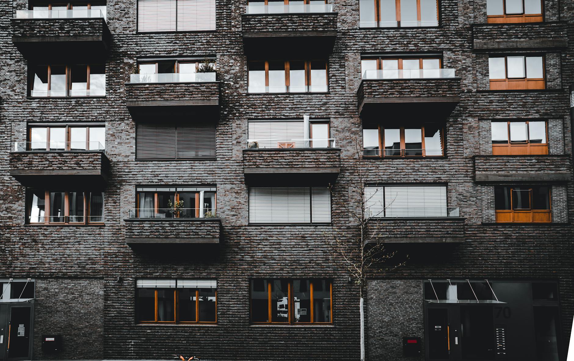 Ceglana elewacja nowoczesnego budynku z balkonami i dużymi oknami
