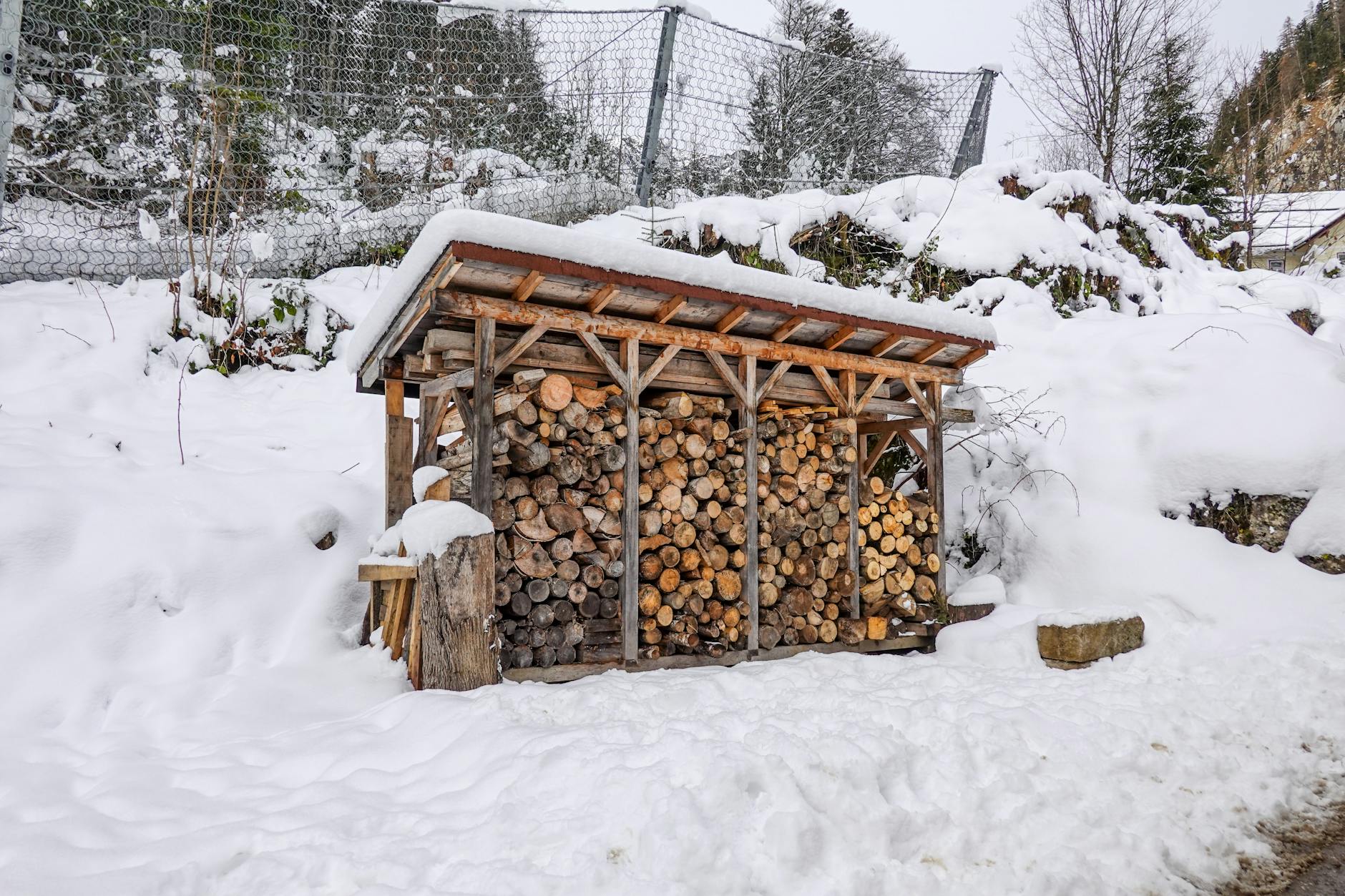Drewniana wiata na drewno opałowe w zaśnieżonym ogrodzie