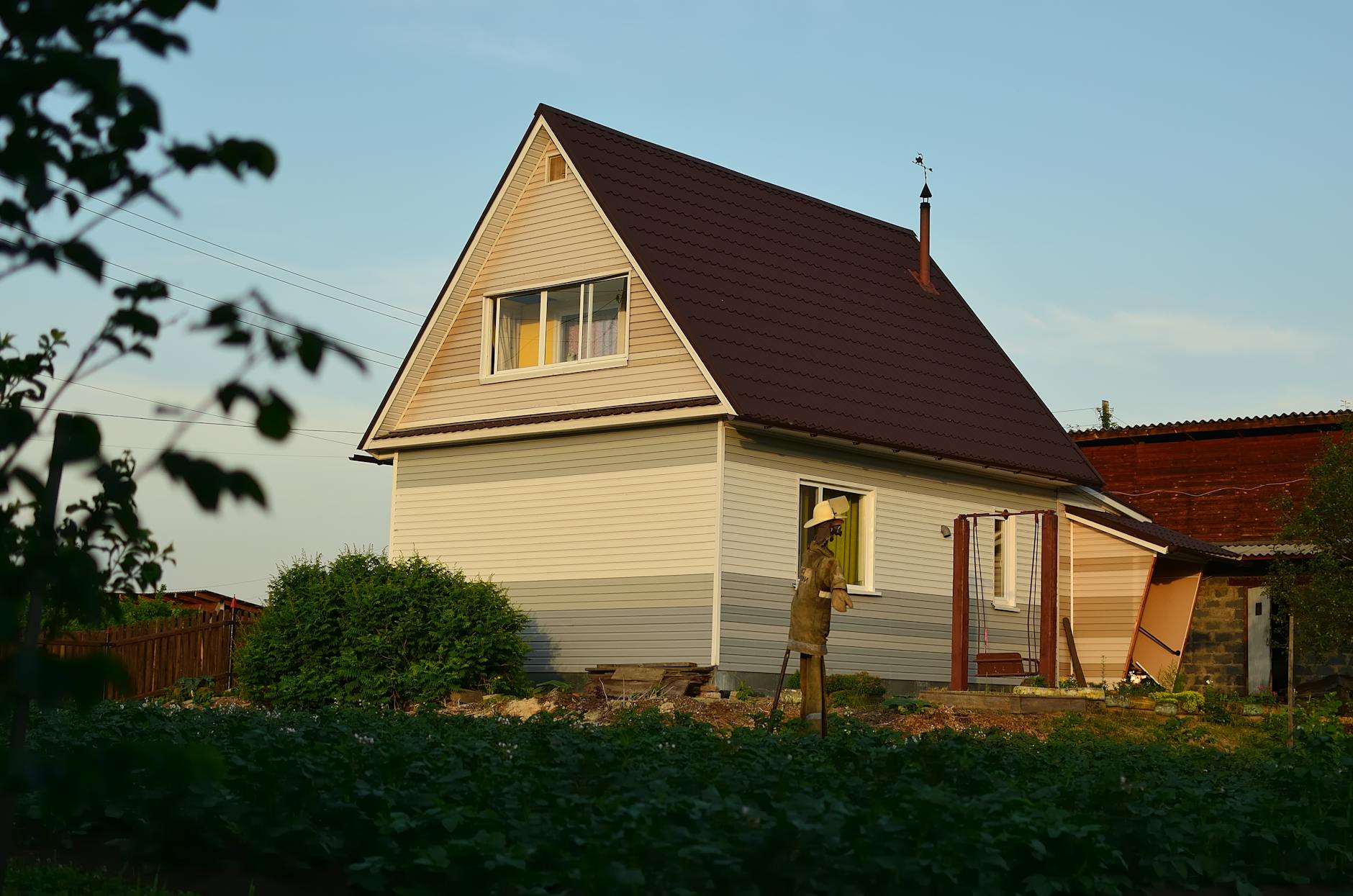 Parterowy dom podmiejski z ogrodem i strachem na wróble o zachodzie słońca