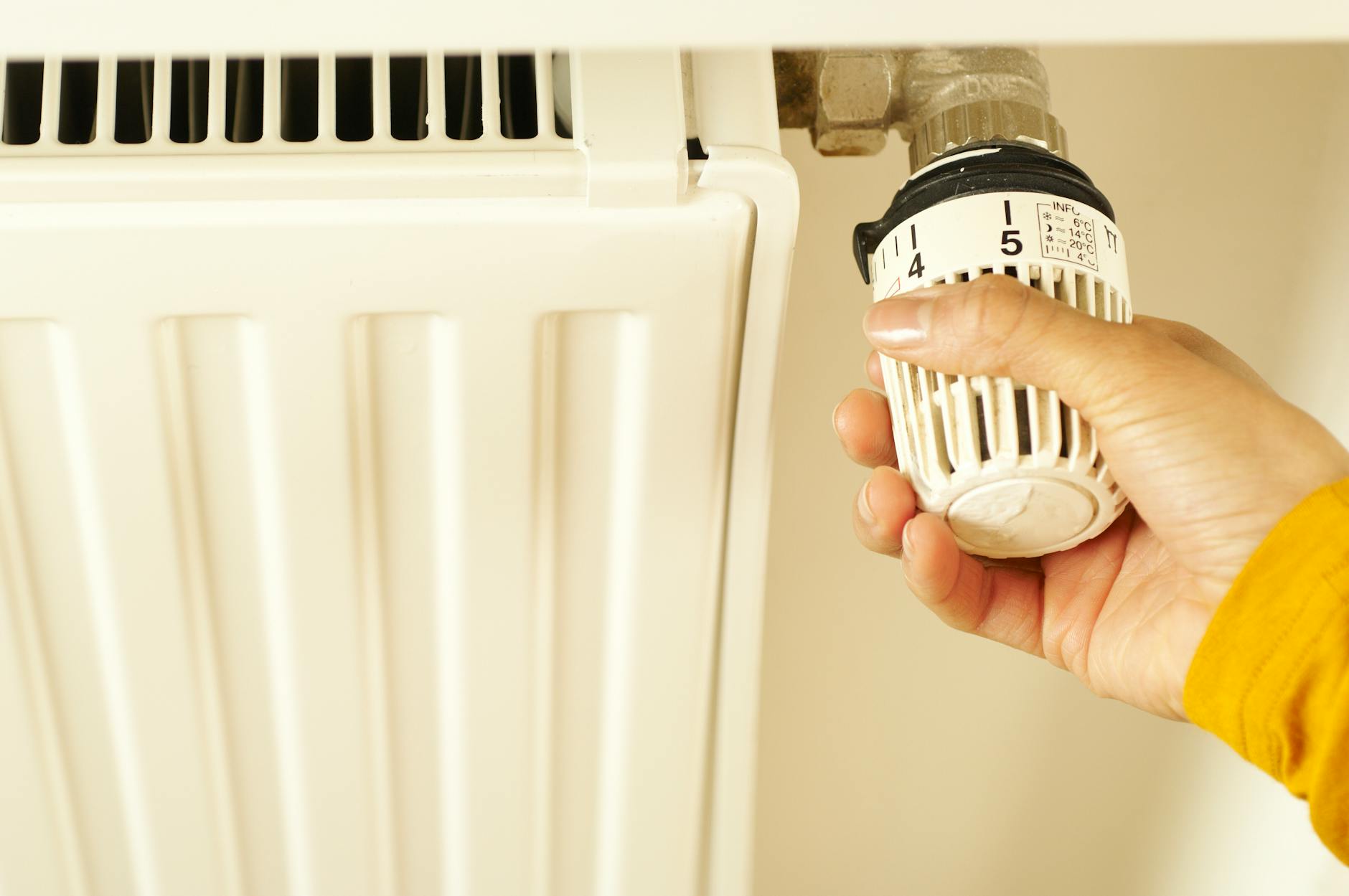 Ręka regulująca termostat grzejnika w celu ustawienia temperatury ogrzewania