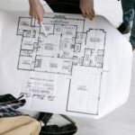 Architekci analizują szczegółowy rzut małego domu na stole