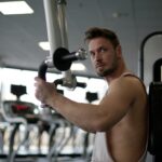 Skupiony mężczyzna ćwiczy biceps na siłowni