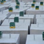 Zbliżenie na betonowe bloczki fundamentowe z wystającymi prętami zbrojeniowymi