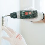 Elektryk w rękawicach montuje gniazdko w ścianie w łazience