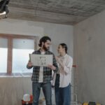 Para ogląda projekt budowlany w remontowanym pokoju domu
