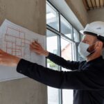 Architekt w kasku analizuje plany budowy na placu budowy
