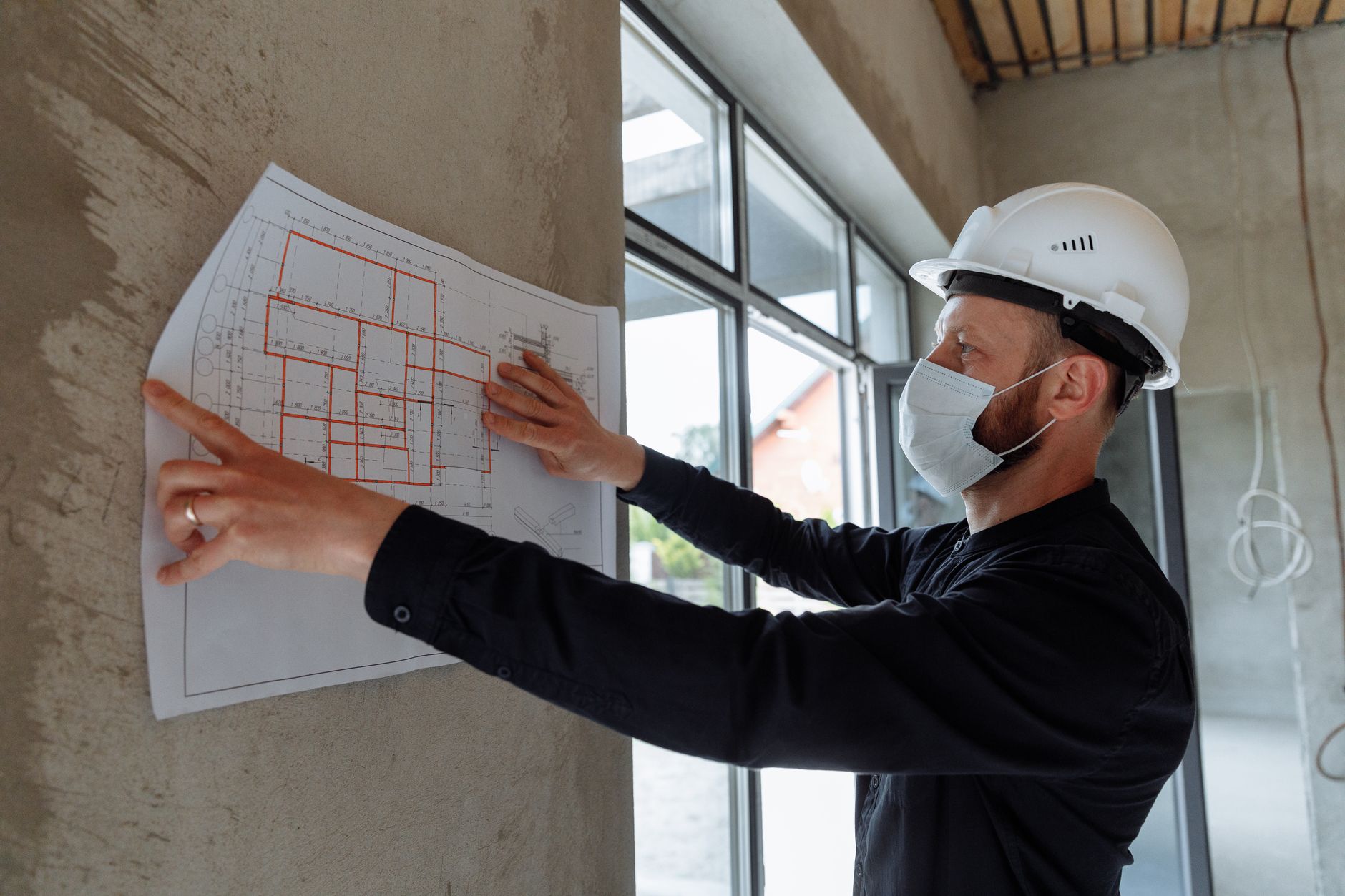 Architekt w kasku analizuje plany budowy na placu budowy