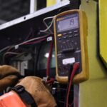 Elektryk mierzy parametry przewodów w panelu sterowania multimetrem